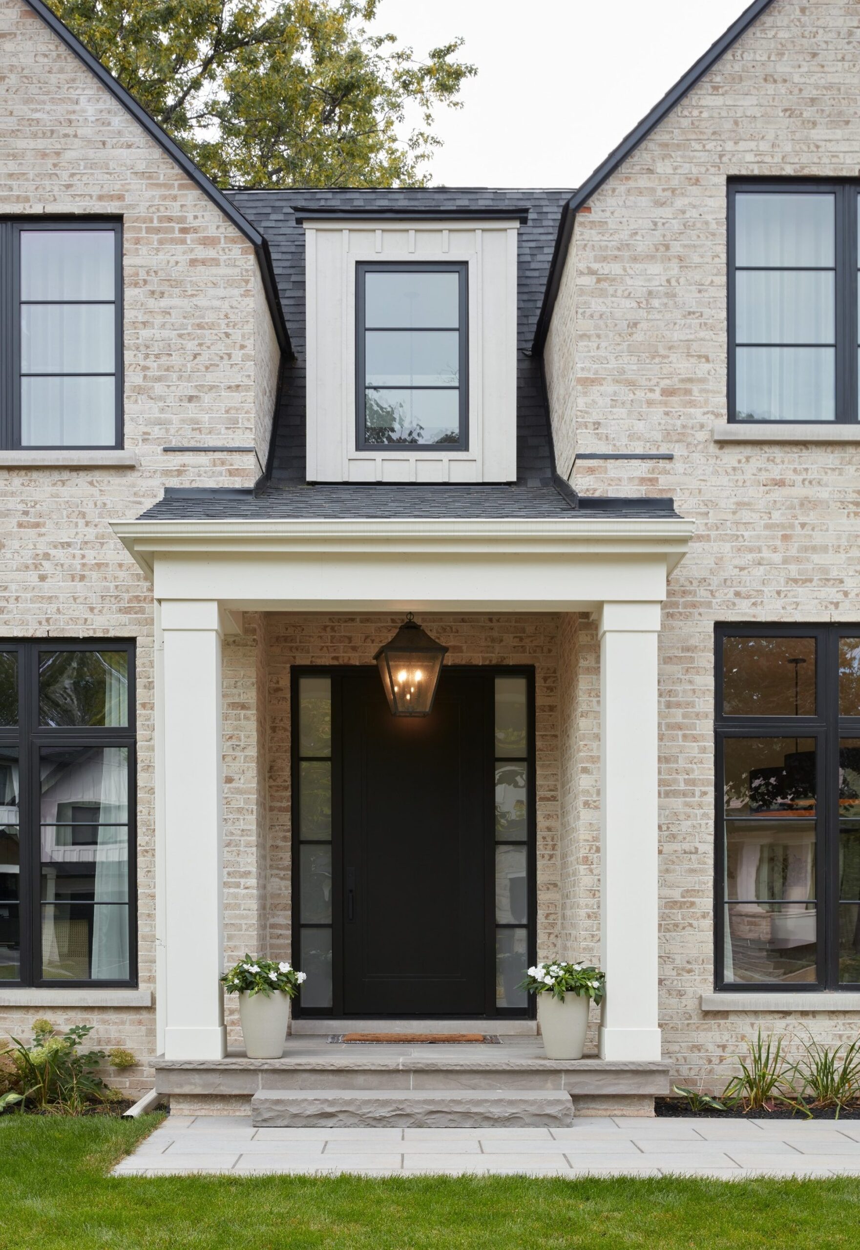 Luxury custom home front entrance in Oakville built by Prasada Custom Homes, featuring traditional brick, black windows, and a timeless covered porch