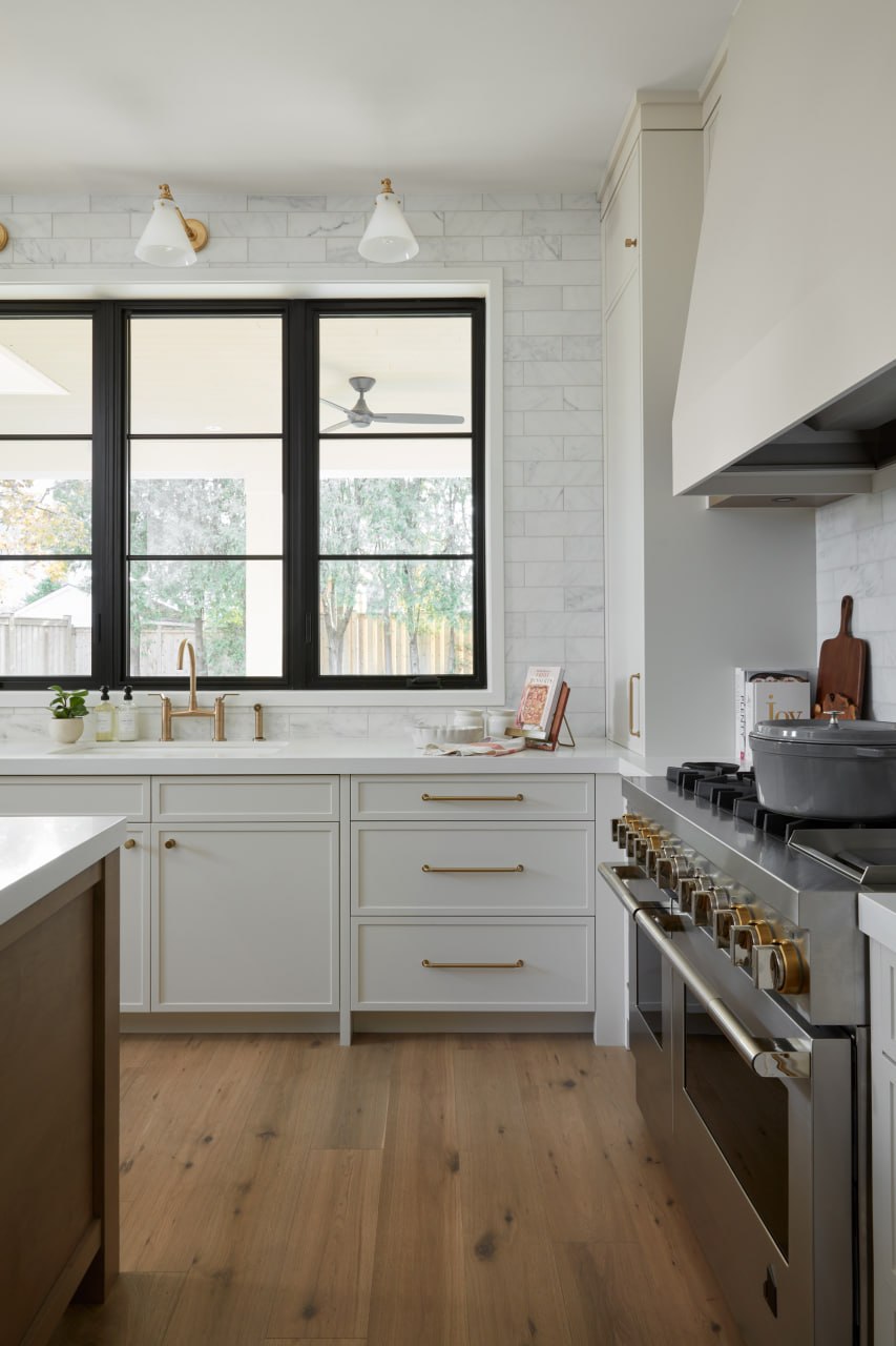 Luxury custom kitchen with white shaker cabinetry, brass hardware and marble subway backsplash