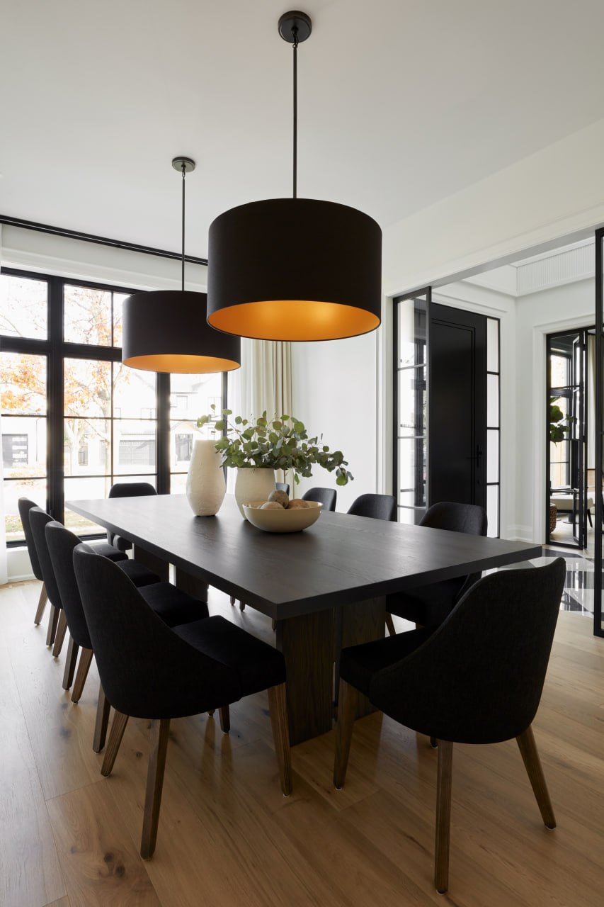 Custom dining room with oversized black pendant lights lined in gold above a dark wood table