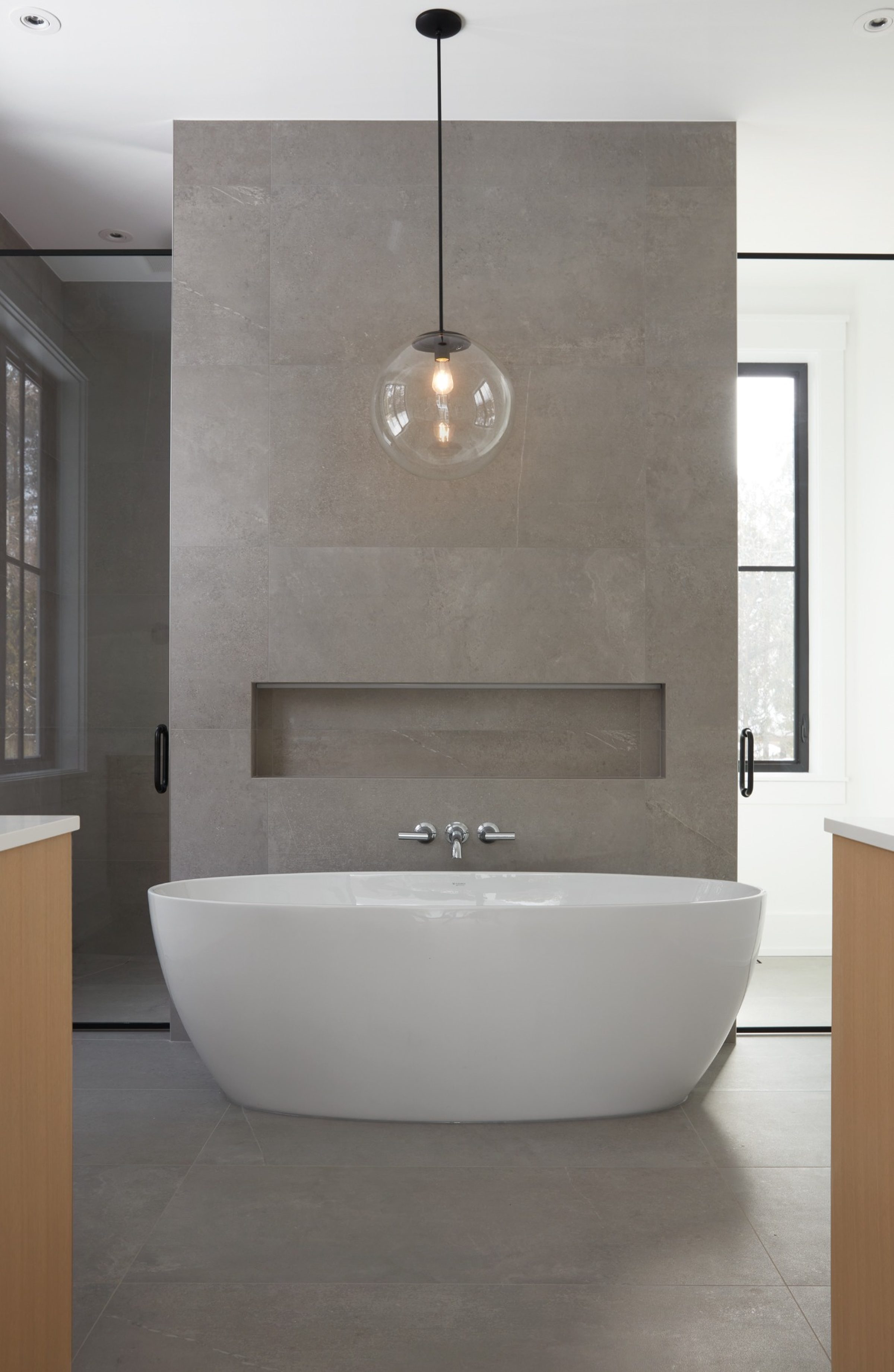 Luxury primary bathroom featuring a freestanding tub and stone feature wall in a custom Oakville home by Prasada Custom Homes