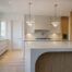 Luxury custom kitchen in Oakville featuring a curved waterfall island, marble countertops, custom wood millwork, and designer pendant lighting by Prasada Custom Homes